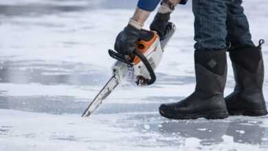 a man holding a chainsaw on top of ice