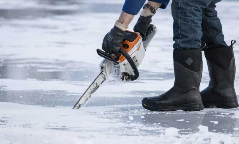 a man holding a chainsaw on top of ice