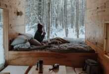 woman sitting on bed watching by the window during winter