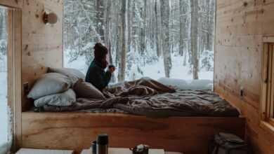 woman sitting on bed watching by the window during winter