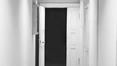 a long hallway with white walls and a black door