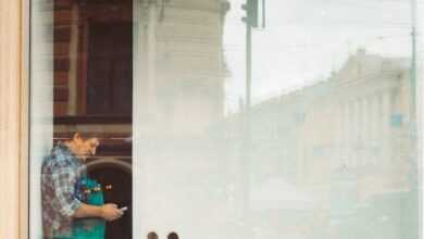 woman in blue denim jacket and blue denim jeans standing in front of glass window