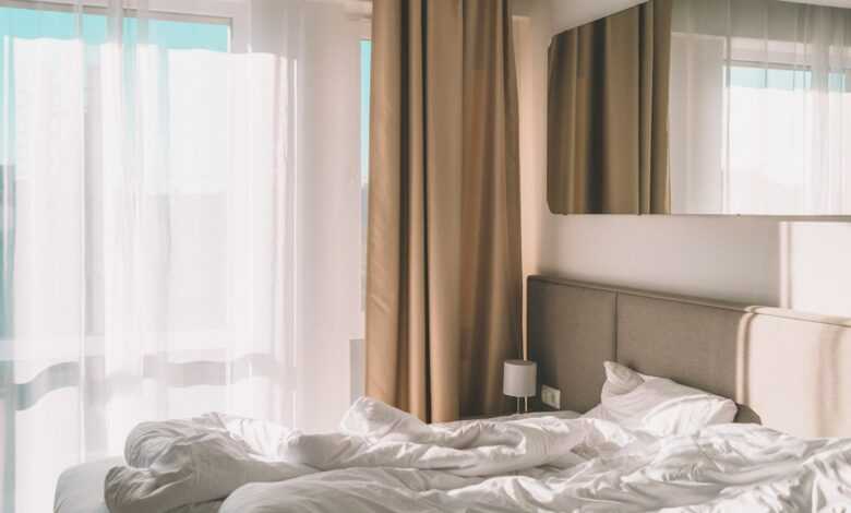 white bed linen near white window curtain