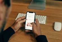 man holding phone while leaning on table